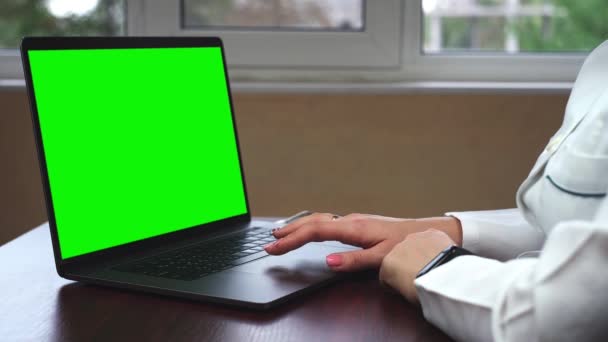 Yakın çekim yeşil ekran ile bir dizüstü bilgisayar üzerinde çalışan bir doktor bir kadeh. Bilim adamı ile chroma anahtar yeşil ekran laptop kullanıyor - Video, Çekim