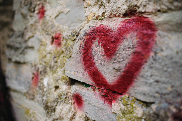 Close up background graffiti silhouette of red heart on an old relief stone wall. - Photo, Image