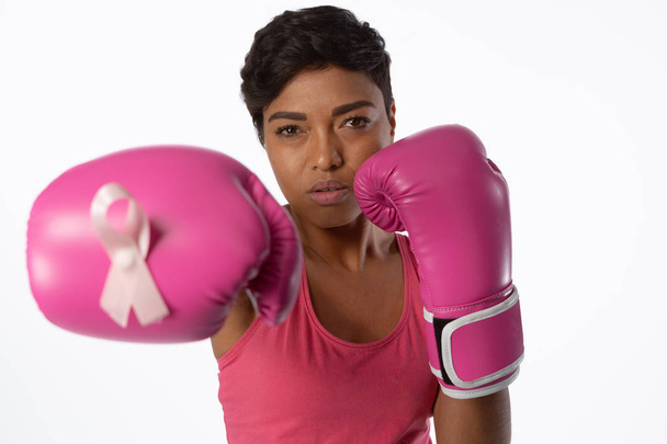 Woman in boxing gloves fighting for breast cancer awareness on white background - Foto, immagini