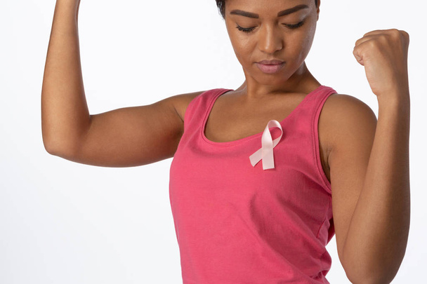 Woman putting up fists and looks at pink ribbon for breast cancer awareness - Foto, Imagen