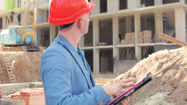 young architect working on a tablet near the construction site - Video, Çekim