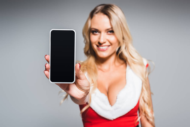 messa a fuoco selettiva di giovane donna in abito di Natale mostrando smartphone con schermo bianco isolato su sfondo grigio
 - Foto, immagini