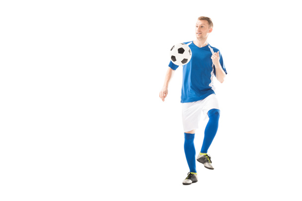 full length view of smiling young sportsman playing with soccer ball and looking away isolated on white - Foto, Imagem