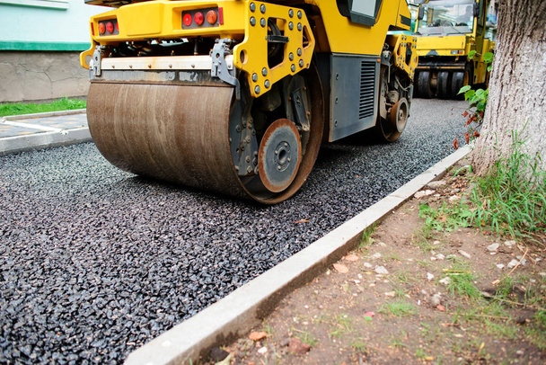 Achtergrond van asfalt roller die stapelen en druk op heet asfalt. Wegreparatiemachine. - Foto, afbeelding