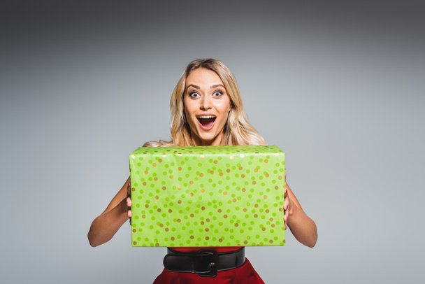surpris belle jeune femme en robe de Noël tenant boîte cadeau isolé sur fond gris
 - Photo, image