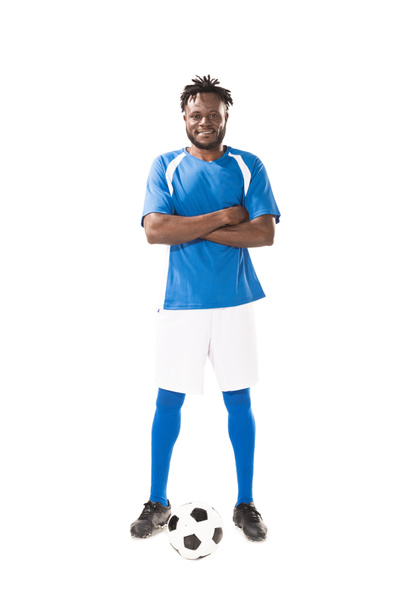 visão completa do sorrindo jogador de futebol americano africano de pé com braços cruzados e olhando para a câmera isolada no branco
  - Foto, Imagem