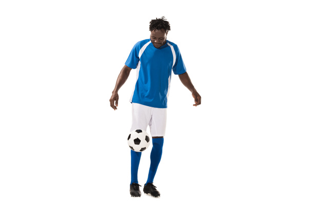 hombre afroamericano deportivo en uniforme de fútbol jugando con pelota aislada en blanco
 - Foto, Imagen
