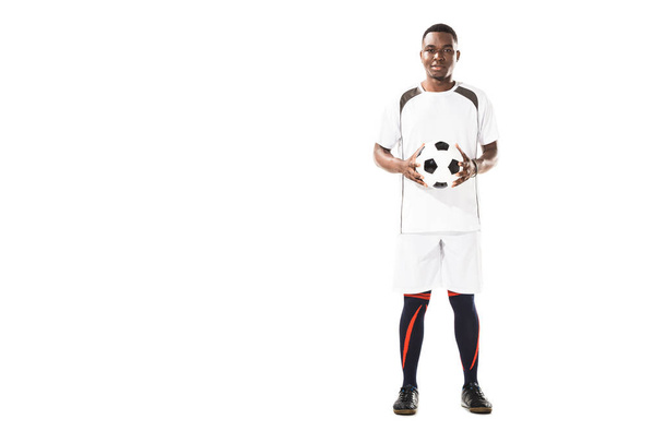 vista completa de feliz joven afroamericano jugador de fútbol sosteniendo la pelota y sonriendo a la cámara aislado en blanco
 - Foto, imagen