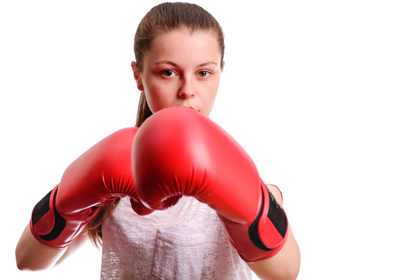 Una giovane donna-pugile sportiva posa davanti alla macchina fotografica in guanti da boxe rossi. Lei si concentra e in piedi nel rack da battaglia
. - Foto, immagini