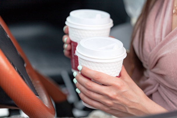 Closeup shot of hands of female driver who holds two paper cups with tea or coffee - Photo, Image