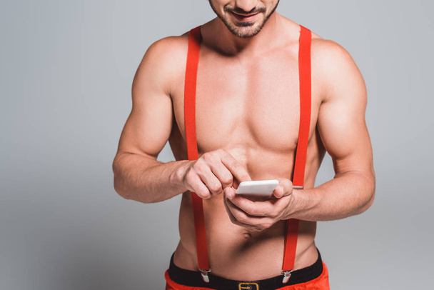 partial view of sexy man in christmas hat using smartphone isolated on grey background - Fotografie, Obrázek