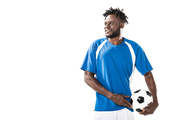 bonito sorrindo afro-americano jogador de futebol segurando bola e olhando para longe isolado no branco
 - Foto, Imagem