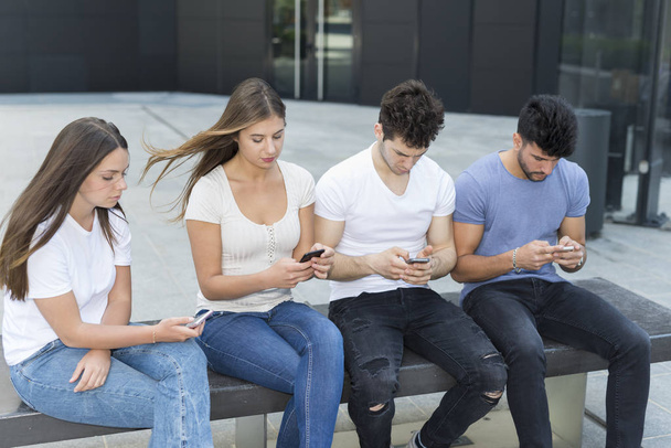 Group of male and female friends each using his cellphone - Photo, image