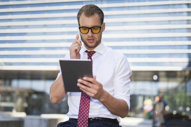 Businessman using a tablet while talking on the cell phone - Foto, Imagem