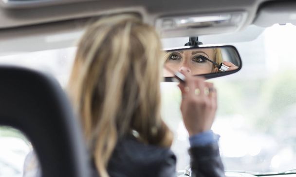 Woman applying makeup on her car - 写真・画像