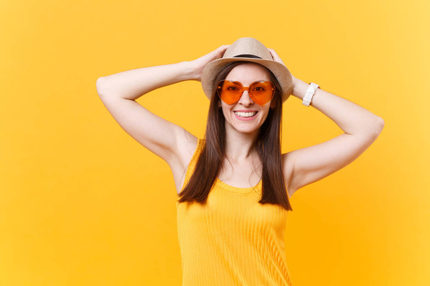 ストロー夏帽子で興奮した笑顔若い女性の肖像画は、オレンジ色のメガネは頭、黄色の背景に分離されたコピー スペースに手を置きます。人々 の心から感情、ライフ スタイルのコンセプト。広告エリア - 写真・画像