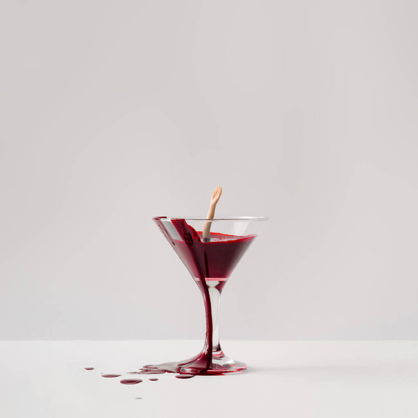 Poupée noyée dans un verre de martini plein de sang. Concept d'Halloween minimal
  - Photo, image
