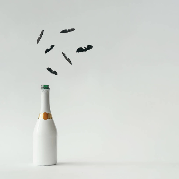 Бутылка шампанского с силуэтами летучих мышей на белом фоне. Концепция Хэллоуина
. - Фото, изображение