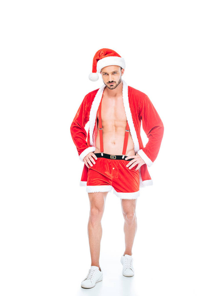 mladý svalnatý muž v kostýmu santa Clause a šortky zobrazující trup izolované na bílém pozadí - Fotografie, Obrázek