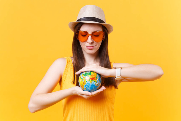 Yaz şapka turist kadın portresi, turuncu gözlük el Globe izole sarı arka plan üzerinde tutun. Hafta sonu kaçış seyahat için yurt dışında seyahat. Hava uçuş yolculuk kavramı. Doğa çöp durdurmak - Fotoğraf, Görsel