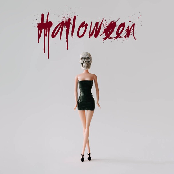 Mädchenpuppe mit Horror-Totenkopf-Kostüm und Text-Halloween. Minimales Urlaubskonzept. - Foto, Bild