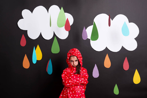 A small girl on a black background with clouds and raindrops. - Zdjęcie, obraz