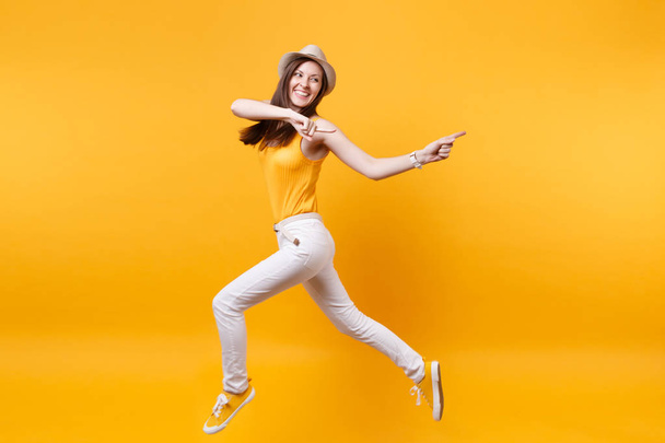Retrato de la joven sonriente feliz saltando mujer alta en sombrero de paja de verano, espacio de copia aislado sobre fondo amarillo naranja. Gente emociones sinceras, pasión concepto de estilo de vida. Área publicitaria
 - Foto, Imagen