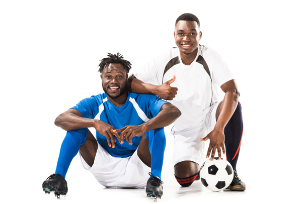 feliz afroamericano futbolistas sonriendo a la cámara y mostrando el pulgar hacia arriba aislado en blanco
 - Foto, imagen
