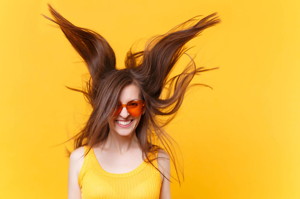 Retrato de risa alegre excitada divertida mujer cómica en gafas de color naranja con el pelo aleteo copia espacio aislado sobre fondo amarillo. Gente emociones sinceras, concepto de estilo de vida. Área publicitaria
 - Foto, imagen