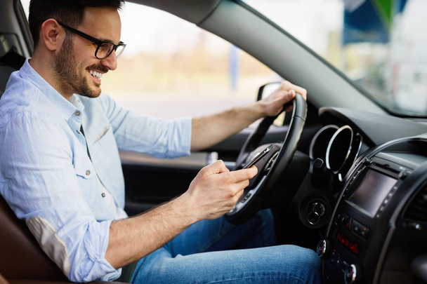 Man looking at mobile phone while driving a car. - Foto, Imagen