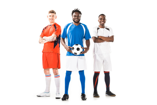 повнометражний вид на багатоетнічних молодих футболістів, що стоять разом і посміхаються на камеру ізольовані на білому
    - Фото, зображення