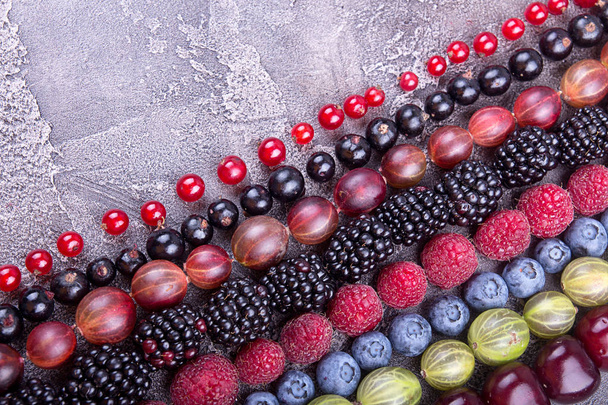 Rows of assorted fruits and berries: sweet cherry, bluberries, raspberries, red and black currant, blackberries. Helthy eating food concept. Top view. Copy space. - Photo, Image