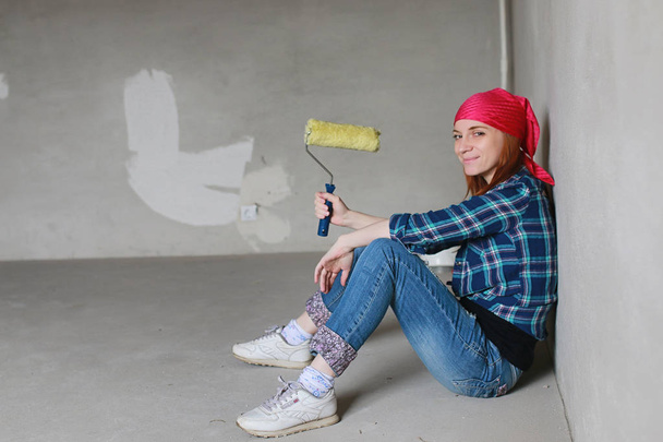 The girl is doing repairs in the apartment. Home moving to a new apartment. The worker makes repairs, plastered and drills the wall. - Foto, immagini