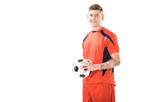 happy young athletic man in sportswear holding soccer ball and smiling at camera isolated on white  - Valokuva, kuva