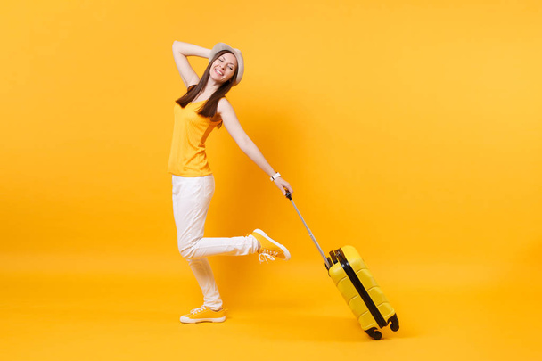 Viajante mulher turista em roupas casuais de verão, chapéu com mala isolada no fundo laranja amarelo. Passageiro viajando para o exterior para viajar nos fins de semana de fuga. Conceito de viagem aérea
 - Foto, Imagem