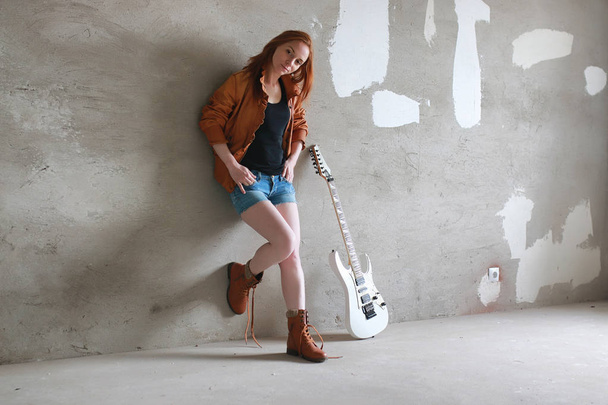 Young red-haired girl with an electric guitar. Rock musician gir - Valokuva, kuva