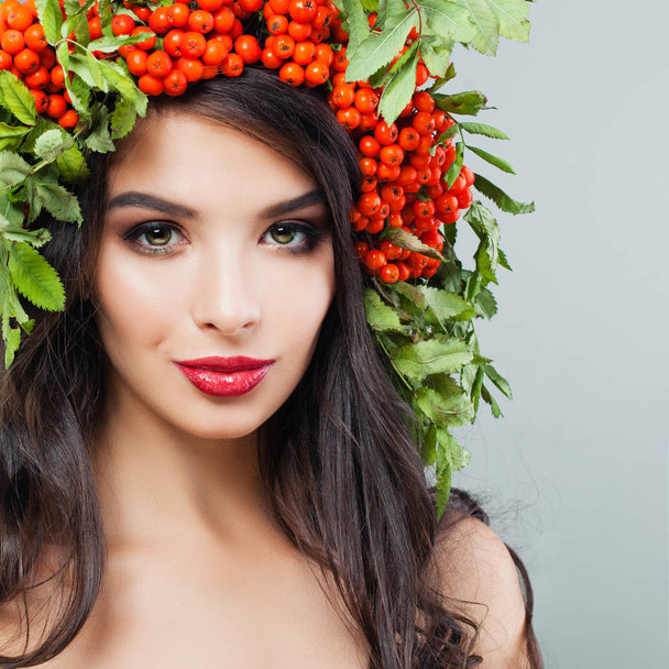 赤い唇メイク、長いウェーブのかかった髪、ローワンと陽気な若い女性ブルネット果実および葉の花輪 - 写真・画像