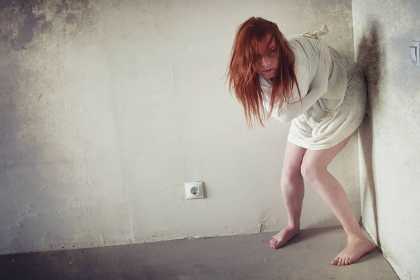 A girl with red hair in a shirt. Domestic violence and sacrifice. Girl with a sick psyche. - Photo, Image