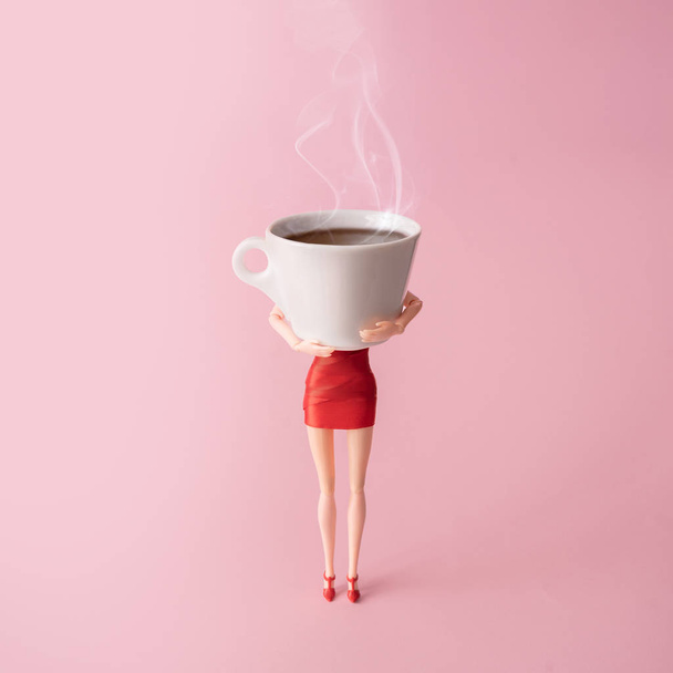 Menina boneca em vestido vermelho segurando grande xícara de café fumegante contra fundo rosa pastel. Conceito mínimo de dependência de café
  - Foto, Imagem