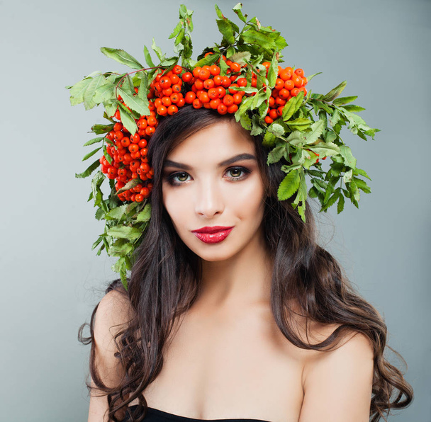 健康な巻き毛のヘアスタイル、メイク、赤い果実や髪で緑の葉を持つ若いブルネットの女性ファッションモデル - 写真・画像
