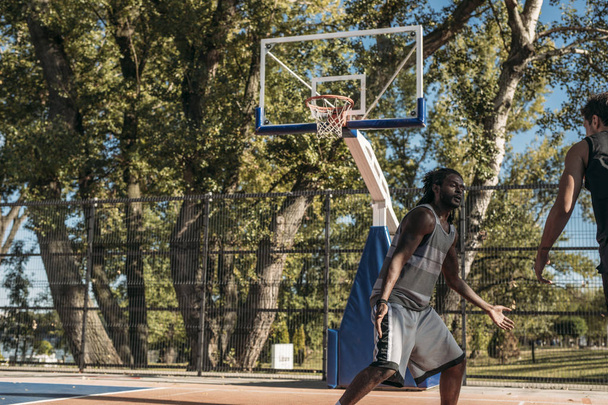 Two man playing basketball at outdoor court. - 写真・画像