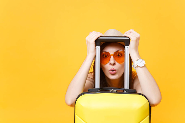 夏のカジュアルな服帽子の楽しい旅行観光女黄色オレンジ色の背景に分離されたスーツケースに目を通します。週末の息抜きに旅行に海外旅行の乗客。空気飛行概念 - 写真・画像