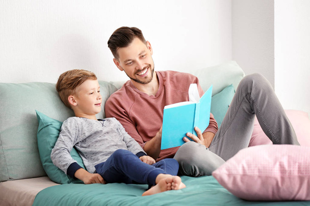 Apa és fia együtt könyvet olvas otthon - Fotó, kép