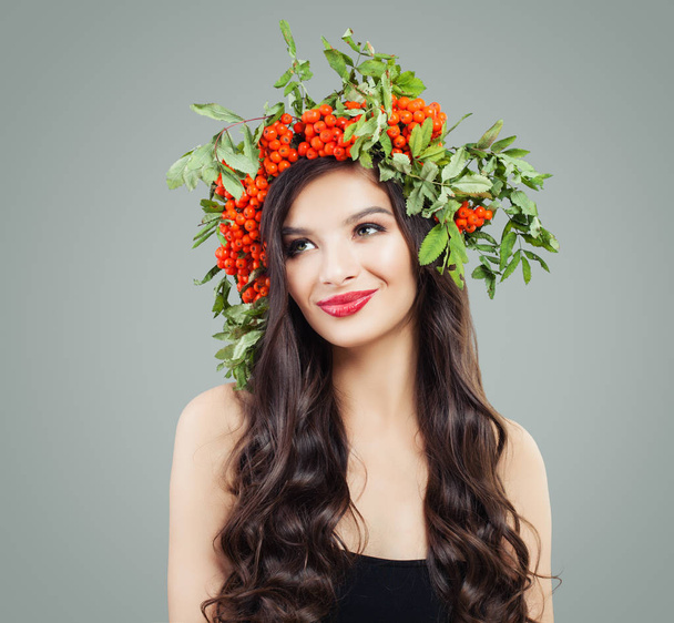 Brunette lady with curly hairstyle and makeup smiling and looking up. Gorgeous woman in natural floral wreath - Foto, Imagem