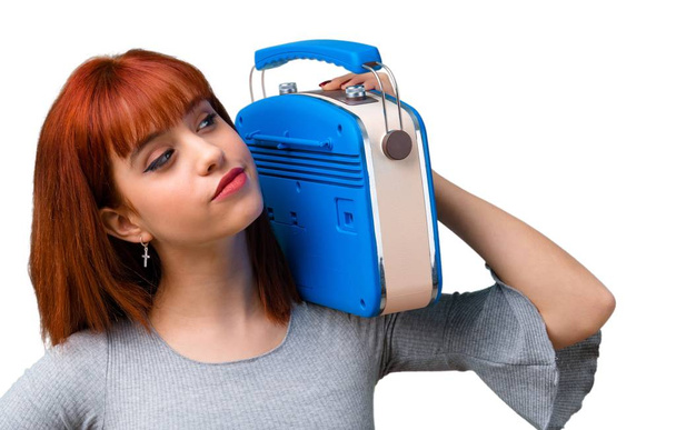 Young redhead girl holding a blue vintage radio - Foto, afbeelding
