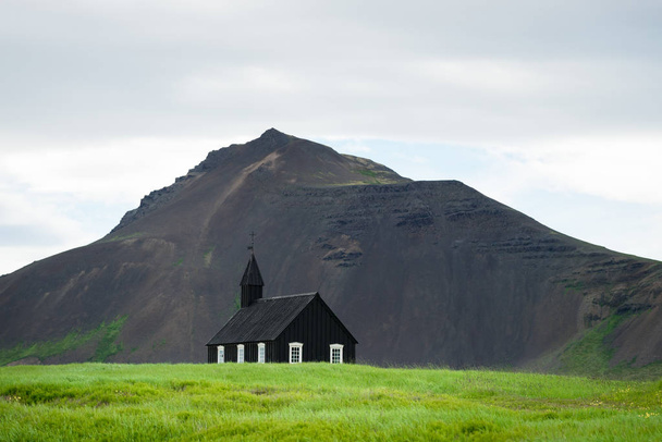 Budir church in Iceland. Black chapel on the background of the mountain. Summer Landscape. Religious and tourist attraction - Zdjęcie, obraz