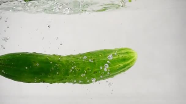 El pepino verde cae en el agua con salpicaduras y burbujas, primer plano en cámara lenta
 - Metraje, vídeo