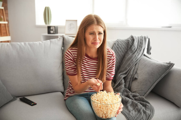 emocjonalna młoda kobieta jedząca popcorn podczas oglądania telewizji w domu - Zdjęcie, obraz