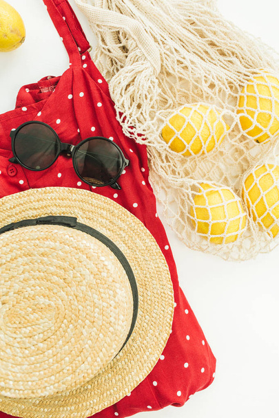 夏の女性のファッションの組成物。赤いドレス、わら、ひも付きの袋、サングラス、レモン。フラット横たわっていた、トップ ビュー. - 写真・画像