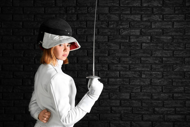 Young female fencer on dark background - Foto, imagen